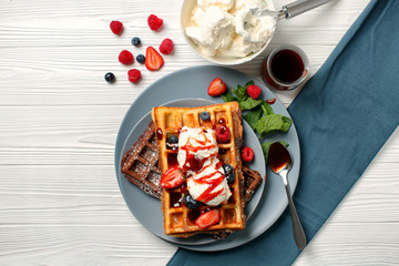 Delicious waffles with berries and ice cream on wooden table