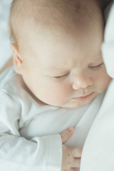 newborn baby sleeps in the arms of a parent. portrait of infant. soft tinted