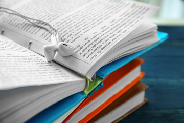 Obraz premium Modern earphones on open book, closeup. Concept of audiobook