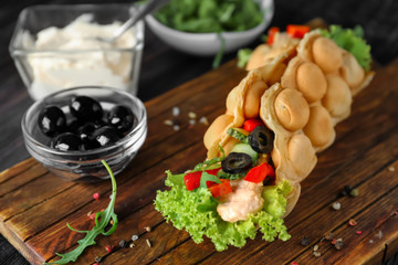 Delicious bubble waffle with meat and vegetables on wooden board
