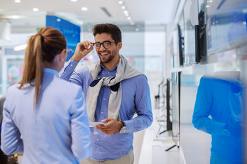 Multiracial couple at tech store looking for a new TV for their home.