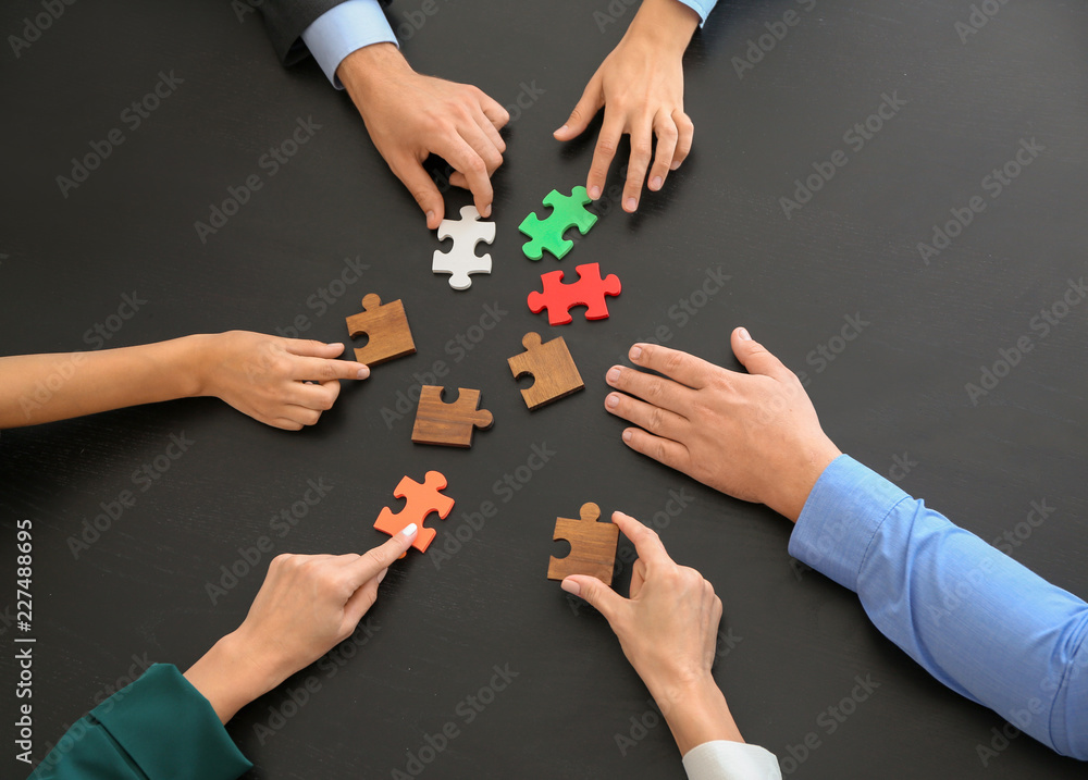 Wall mural business team assembling puzzle on dark table