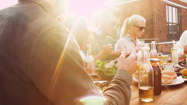 leisure and people concept - happy friends having dinner or bbq party and eating on rooftop in summer