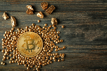 Gold nuggets and bitcoin on dark wooden background