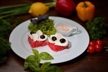 tomato carpaccio with mozzarella and and olives on a white plate
