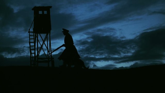 A communist militiaman guarding the border with his dog. Eastern Bloc Countries during the Cold War.