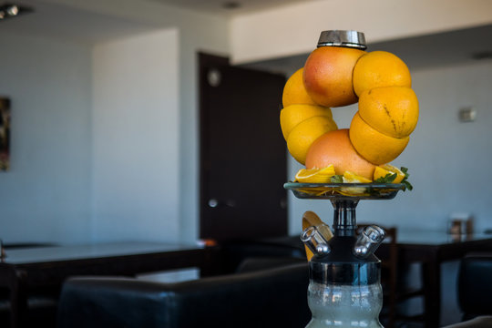 Beautiful glass hookah, with a fruit bowl, consisting of oranges and grapefruit.