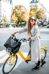 Portrait of a young stylish woman with yellow bicycle on the street in Paris