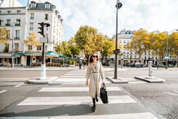 Morning street view with stylish woman crossing the street in Paris, France