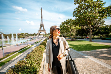 Lifestyle portrait of a young woman walking in front of the famous Eiffel tower during the sunny...