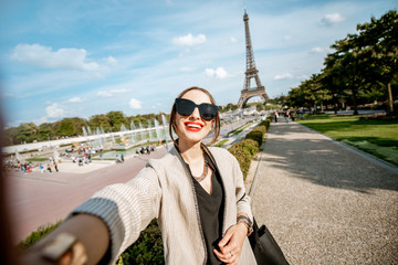 Lifestyle portrait of a young woman walking in front of the famous Eiffel tower during the sunny day in Paris