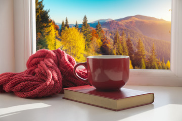 window with autumn leaves, a book, a mug of tea
