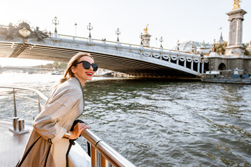Young woman enjoying beautiful landscape view on the riverside from the tourist ship during the...