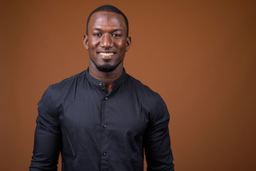 Obraz premium Portrait of handsome African businessman against brown background