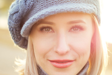 Young blonde happy smiling naive glance woman in French blue beret coat and warm hat outdoor closeup portrait perfect skin and day makeup in the autumn park. Cold outside. Winter spring clothes