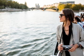 Young woman enjoying beautiful landscape view on the riverside from the ship during the sunset in Paris