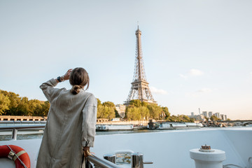 Young woman enjoying beautiful landscape view on the riverside with Eiffel tower from the boat...