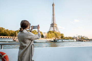 Young woman enjoying beautiful landscape view on the riverside with Eiffel tower from the boat during the sunset in Paris