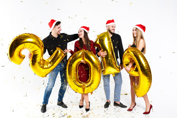 Portrait of an excited, cheerful multinational group of friends in red hats celebrating the New...