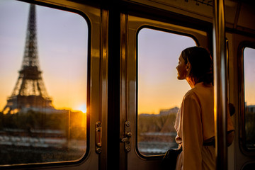 Young woman enjoying view on the Eiffel tower from the subway train during the sunrise in Paris - obrazy, fototapety, plakaty