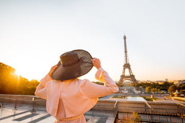 Woman enjoying great view on the Eiffel tower standing back with hat on the square early in the...