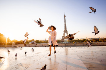 Woman running on the famous square dispersing pigeons with great view on the Eiffel tower early in the morning in Paris - obrazy, fototapety, plakaty