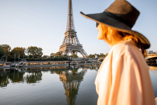 Young woman tourist enjoying landscape view on the Eiffel tower with beautiful reflection on the water during the mornign light in Paris. Image focused on the background