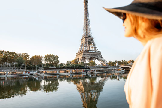 Young woman tourist enjoying landscape view on the Eiffel tower with beautiful reflection on the water during the mornign light in Paris. Image focused on the background