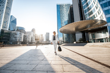 Business woman at the financial district with beautiful skyscrapers on the background during the morning light in Paris. Wide panoramic view - obrazy, fototapety, plakaty