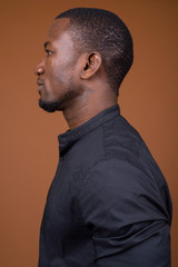 Portrait of handsome African businessman against brown background