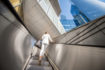 Geometrical view from below on the modern financial district with business woman going up on the...