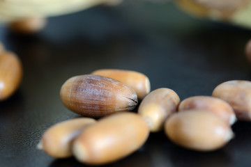 Acorns and dry oak leaves on a dark background close up