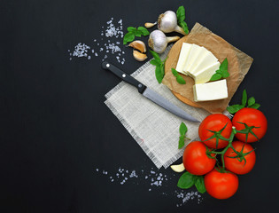 Fresh feta cheese with tomatoes,greens on wooden serving board over wooden background. Food Ingredients, view from above. Healthy food.Top view.