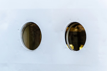 two portholes in the white board of the ship close up