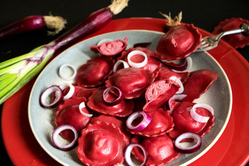 italienische Teigtaschen mit roter Füllung und roten Frühlingszwiebeln