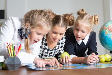 Naklejka premium Group of schoolkids working together at the table at the classroom. happy school time!
