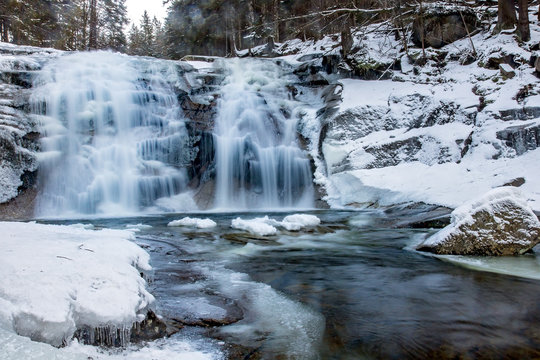 Waterfall in snowy forest. Winter Mumlava Waterfall in Harrachov, Krkonose mountains, Czech Republic