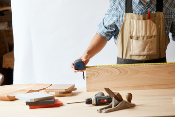 Home repair concepts. Handicraft Carpentry. Cabinet-maker hands measuring a wooden plank using...