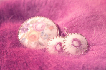 Vintage jewelry close up on fluffy pink knitted background. Old retro ancient pendant and earrings,...