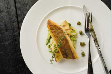 Fillet of halibut on a pillow of stewed leeks on the white plate.
