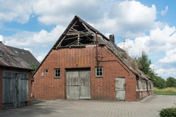 Fototapeta na wymiar Bauernhaus mit Scheune und einem beschädigten Reetdach