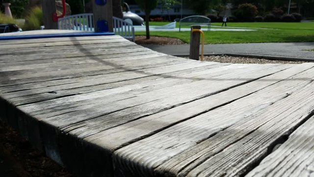 Child running back and forth on a wooden bridge at a playground/ park
