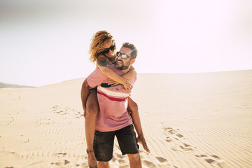 happiness concept with middle age people man carrying woman on his back walking on the soft sand of...
