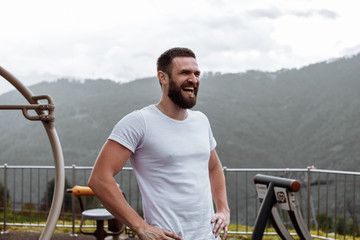 Handsome muscular hunk man looking at highlands landscape with foggy sky from the peak of the mountain, feeling hapyness and joy. Showing Healthy Body While Looking At Horizon