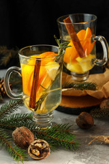 Winter ginger tea with orange and lemon in glass cups. Cinnamon and Rosemary Spices  Decor with Christmas tree branches and cones. Christmas composition.