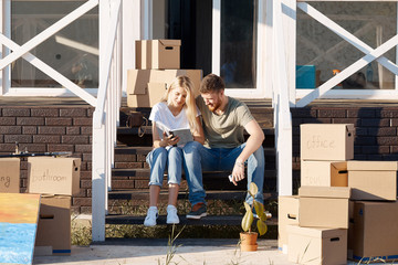 Husband and wife standing in front of new buying home with boxes. bought first home