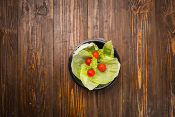 Green leaf lettuce on the plate with cherry tomatoes