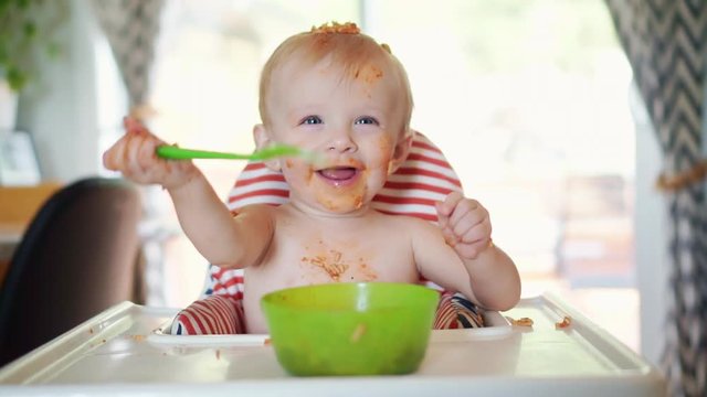 Little baby eating spaghetti dinner and making a mess