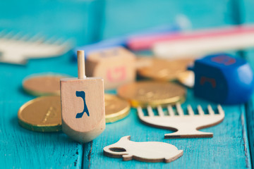 Hanukkah dreidels with some Hanukkah coins and Hanukkah candles on a vintage wood green background....