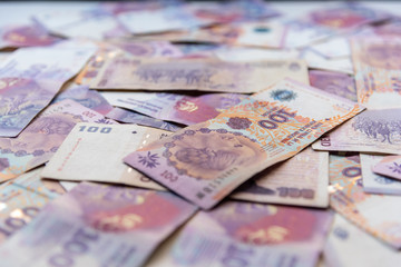 Obraz na płótnie Canvas Argentinian one hundred pesos bill money scattered on a table